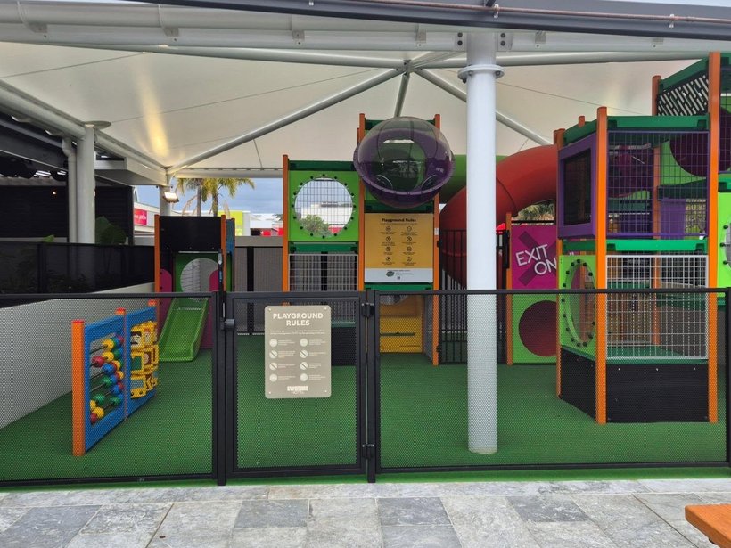 Colourful multi-level play structure behind a see-through Perf Safe fence